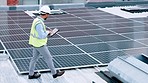 Electrician checking solar panels technology on the roof of the building his working on. Professional engineer technician wearing a safety helmet looks closely at his modern renewable energy design
