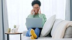 Happy student talking on phone with a classmaate while working on an assignment on her laptop. Young and edgy African American female with afro wearing glasses relaxing on a sofa studying online