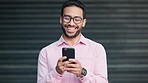 Cheerful, happy and carefree man smiling and laughing while texting on a phone outdoors. Trendy young guy chatting to his friends on social media, browsing online and watching funny internet memes