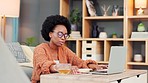 Entrepreneur talking on phone call and discussing a business plan with a colleague or client while typing on a laptop and taking notes in a diary. One black female freelance worker working from home