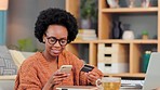 Excited, happy and cheerful woman celebrating while online banking with credit card and phone in a home living room. Smiling young woman with afro dancing after checking her finance app on technology