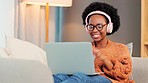 Carefree, happy and relaxed woman listening to music and dancing while streaming on her laptop with headphones. Young female enjoying time off during the weekend, smiling and feeling positive at home