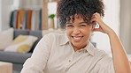 Portrait of relaxed, happy and stressless female relaxing on the couch and listening to music on earphones at the end of a work day. African american female laughing while enjoying a podcast at home