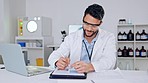 Smart smiling male scientist feeling confident about science test results. Young intern writing and working on a computer with a smile in a laboratory. Portrait of a lab worker happy with his success