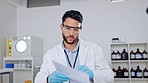 Serious, focused and confident young scientist working in a laboratory and reading paperwork while conducting research and experiments. Medical and healthcare worker looking over science information