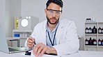 Doctor writing a medical healthcare prescription at work in his office. Close up of a young and serious medic professional with a beard wearing safety glasses filling out a health check report