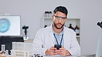 Happy scientist checking social media on his phone while on a break and wearing safety glasses and a lab coat. Young male chemist or medical researcher typing emails and looking relaxed in laboratory