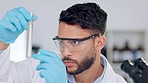 Focused, confident and professional male chemist analyzing a test tube. Close up of a young man studying liquid sample contained in a test tube. Chemistry, Science, Research and Development concept