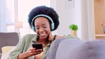 Happy, carefree and smiling woman laughing, reading a message on a phone and listening to music while relaxing on a sofa at home. Fun, playful and trendy young female enjoying a joke on social media