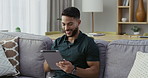 Happy, relaxed and carefree man with a tablet, browsing social media and surfing the internet at home. A cheerful and smiling guy reading news and posting online while sitting on living room sofa