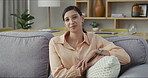 Happy, smiling and resting woman sitting, relaxing on the couch in the lounge alone at home. Portrait of one comfy, cozy and content female looking relaxed, peaceful and calm on a sofa