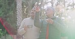 Mature couple enjoying retirement, laughing and bonding outside while drinking coffee, tea and hot drink. Senior woman talking, pointing and showing elderly man in a home garden, backyard and yard