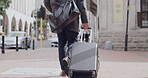 Casual travel or a man carrying a suitcase and slowly walking to a hotel or airport in the city of London. Back view of a male with bags or luggage in an urban town traveling for a holiday