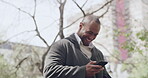 Happy man texting and celebrating good news while walking in the city. Cheering man showing winning gesture after reading an email about a new job or promotion. Guy excited about positive feedback
