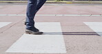 Closeup of feet walking over a public crossing, zebra cross and urban street in a city or town. A casual male walk on white lines during a green light and follow road rules and safety outside
