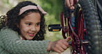 Cute, happy, and carefree girl fixing and repairing a bicycle with her father outside. Cheerful, curious and helpful daughter learning to use tools on a bike with her dad in a backyard or park