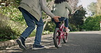 Young girl learning to ride a bicycle in the neighborhood. Loving, caring and proud grandparent helping grandchild to cycle on her own, motivated and determined child cycling in the outdoor nature.