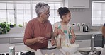 A young child smiling, laughing and playing with her grandparents while learning, baking or cooking. A little girl, grandfather and grandmother bonding, having fun and spending quality time together.