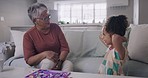 Grandmother and grandchild bonding, playing and spending time together during a visit at home. Grandparent and grandchild enjoying free time, feeling happy, carefree and smiling in the living room