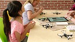 Students building, testing and designing scientific drones, batteries and electrical equipment from tablet. Group of diverse children following engineering tutorial for middle school science project