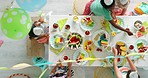 Birthday party, balloons and cake being enjoyed while children celebrate together at a rainbow decorated table from above. Summer fruits and sweet treats being served while kids have fun together