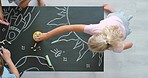 Creative, drawing and fun activity in a kids classroom with chalk and blackboard from above. Group of diverse children learning together and creating an interactive, educational art project in class