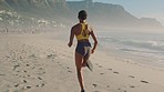 Active, sporty and athletic woman running, training and doing cardio on the beach during summer from behind. Fit, energetic and fast female athlete, doing a workout, exercising and jogging at the sea