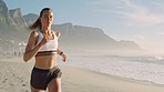 Fitness, health and exercise of active, athletic female running along the beach with earphones. Fit woman jogging, enjoying fresh air while doing cardio workout, practice, speed, energy
