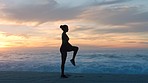 One fit, strong female athlete stretching before a run, jog or exercise. Active, sporty and flexible woman doing a warmup and getting ready for an outdoor workout at the beach at sunset