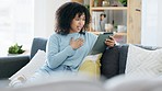 Sad young female on an video call on her tablet feeling upset while sitting alone at home. Stressed woman talking with a friend online. Casual lady stress on a couch while discussing problems