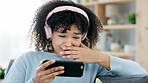 Sad, depressed and frustrated girl watching on phone with headphones. Teenager with Afro feeling emotional over her favorite series in living room. Young female in distress over an online episode