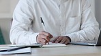 Businessman hands working and writing notes in a diary book with pen planning daily tasks. Creative male writer or journalist making a list of ideas for his article story sitting in home office desk