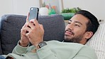 Texting, happy and relaxing man typing on phone while browsing the internet, playing a game or chatting on social media. Male laughing and enjoying mobile app and funny video while streaming at home