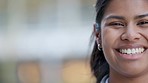 Closeup face portrait of a happy woman smiling, laughing and looking cheerful while standing outside against blurred background for copy space. Head of a young, cute indian female with kind features