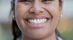 Closeup face portrait of a happy woman smiling, laughing and looking cheerful while standing outside against blurred background for copy space. Head of a young, cute indian female with kind features