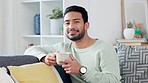 Carefree, relaxed and smiling young man enjoying a cup of tea, coffee or warm drink in the lounge at home. Portrait of a comfortable, happy and handsome guy laughing while enjoying fresh hot beverage