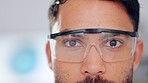 Closeup of male scientist eyes and face wearing safety glasses or goggles for protection from dangerous, hazardous materials. Isolated technician or engineer working in a lab, with bokeh background.