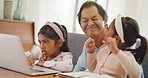 Happy grandfather playing with little girls while browsing on laptop and relaxing at home. Smiling mature male spending quality time with grandchildren being playful. Senior man and kids having fun