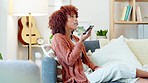 Talking on phone call, networking and voice notes while relaxing on sofa or couch in home living room on weekend. Smiling, happy and expressive woman with afro sharing gossip, news and story on tech