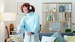 Happy young woman dancing, listening to music and enjoying time alone at home. Feeling carefree in the living room, joyful lady wearing headphones is satisfied with relaxation in leisure time.