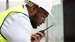 Builder, contractor and technician talking on radio transmitter walkie talkie while managing construction project. Engineer with communication for building plan, industrial logistics and maintenance