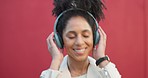 Happy woman with headphone listening to music and dancing against a red studio background. african american female smile, fun and enjoying song with a playful , dance and carefree attitude