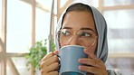 Hijab, Muslim woman and thinking with coffee or Islamic tea at home with peace and calm mindset. Young female from Israel relax looking out a window with a idea and glasses taking a break at a house