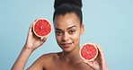 Black woman, beauty and skincare smile with grapefruit against a blue studio background. Portrait of a happy African female model in healthy diet holding juicy vitamin c for skin, facial and body