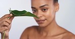 Beauty, plant and water with a woman and a leaf for hydration in studio on a gray background. Natural body skincare with a young female model with a smile and posing for health and wellness