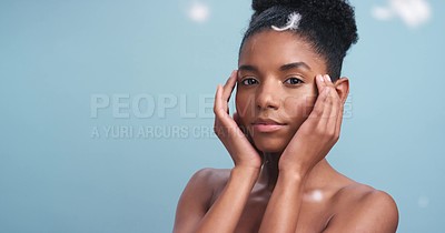 Nude black model with soft skin, feather art fall against blue backdrop
