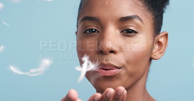 Nude black model with soft skin, feather art fall against blue backdrop