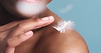 Skincare, feather and black woman at beauty dermatology spa with a shoulder close up in studio with blue background. Lifestyle, wellness and young girl with smooth and healthy body care routine