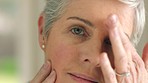 Beauty, face and anti aging with a senior woman touching her face and skin with her hand in a bathroom at home. Skincare, treatment and retirement with an attractive and elderly female pensioner