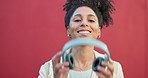 Music, streaming and headphones with a happy woman listening to a podcast, audio or the radio with a smile in studio against a red background. Portrait of a young female enjoying online sound